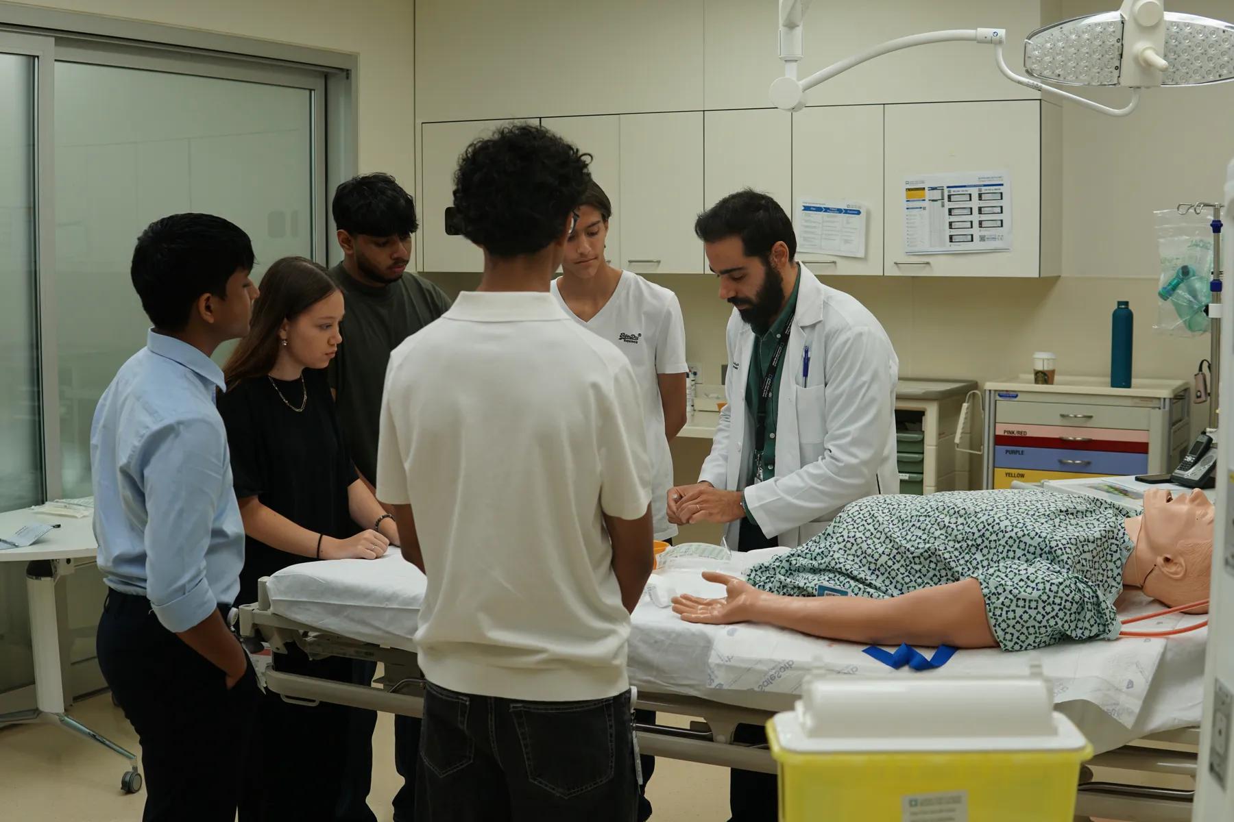 Students around a simulation patient with a doctor