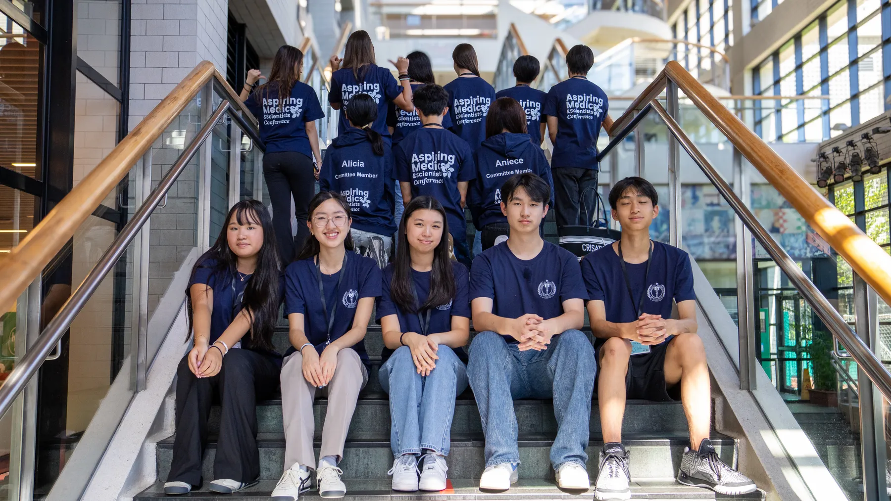 Student ambassadors in conference T-shirts sitting on a staircase
